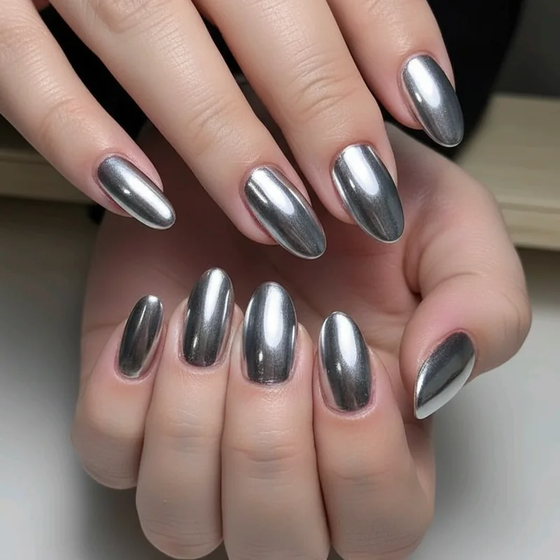 Chrome powder short almond nails with mirror finish creating elongating visual effect on natural nail length
