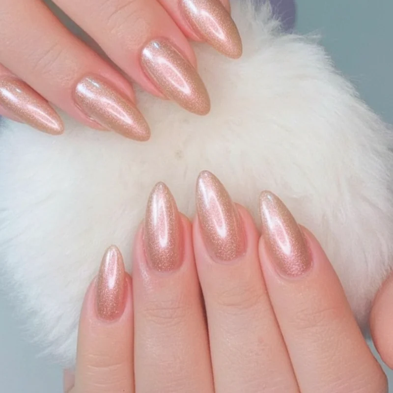 Pearl chrome soft glazed almond nails in champagne and rose gold tones showing diffused light reflection finish for spring 2026