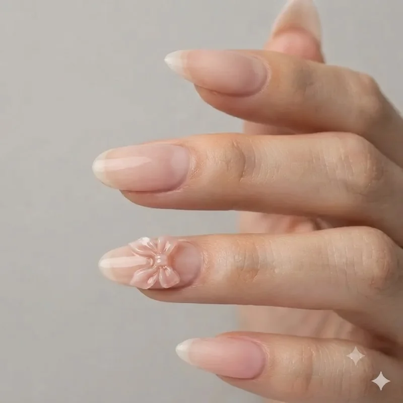 Sculpted 3D bow accent nail on a nude blush base showing dimensional gel construction detail