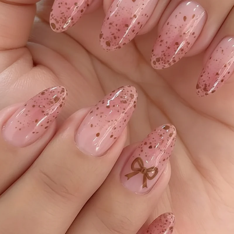 Bambi nails on dusty rose base with tawny speckles and coquette bow accent showing soft romantic deer print nail variation for 2026