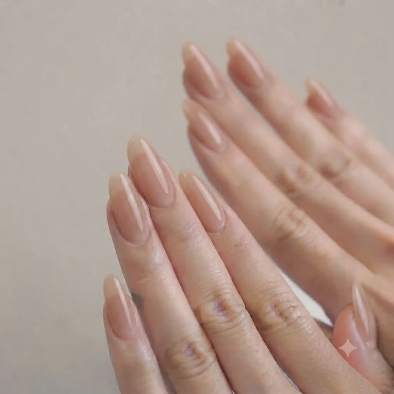 Sheer mocha nude polish swatch on medium length oval nails showing translucent finish