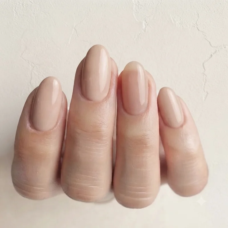 Close-up of sheer nude clean girl manicure on oval shaped nails with glossy finish