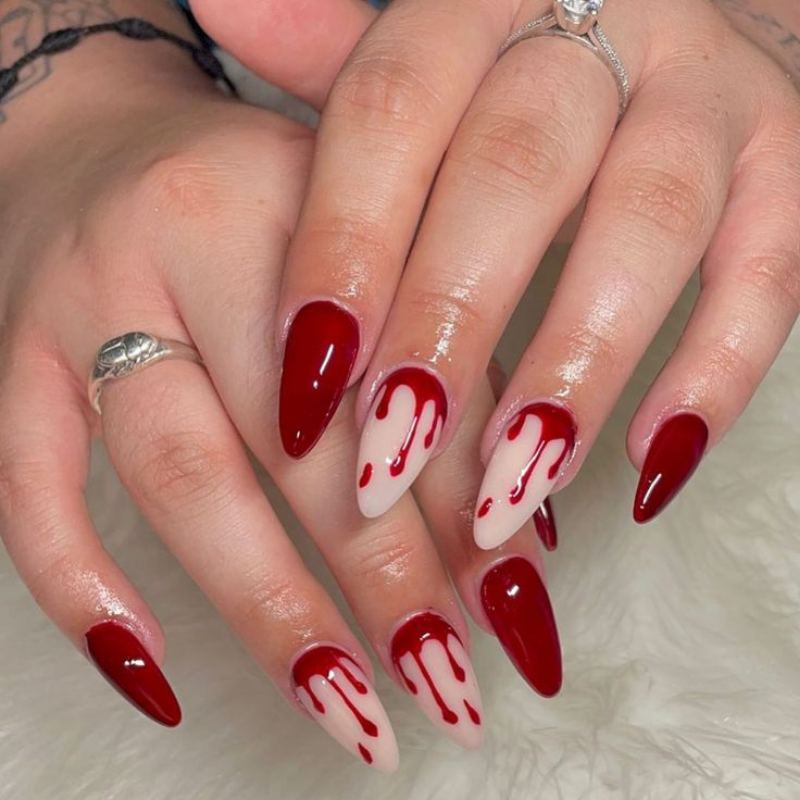 Burgundy red blood drip effect from nail tips on nude base coat for dramatic Halloween nails