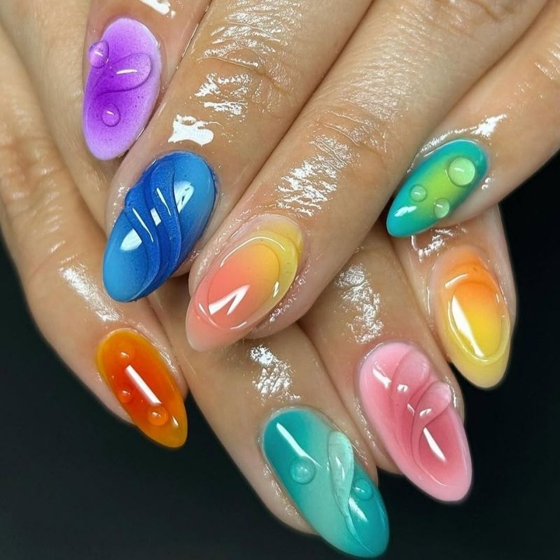 Fun tie-dye nails created with blooming gel featuring rainbow colors and retro swirls