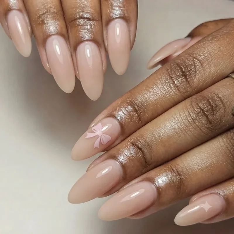 Beginner bow nail sticker design on a nude polish base for an easy accent manicure