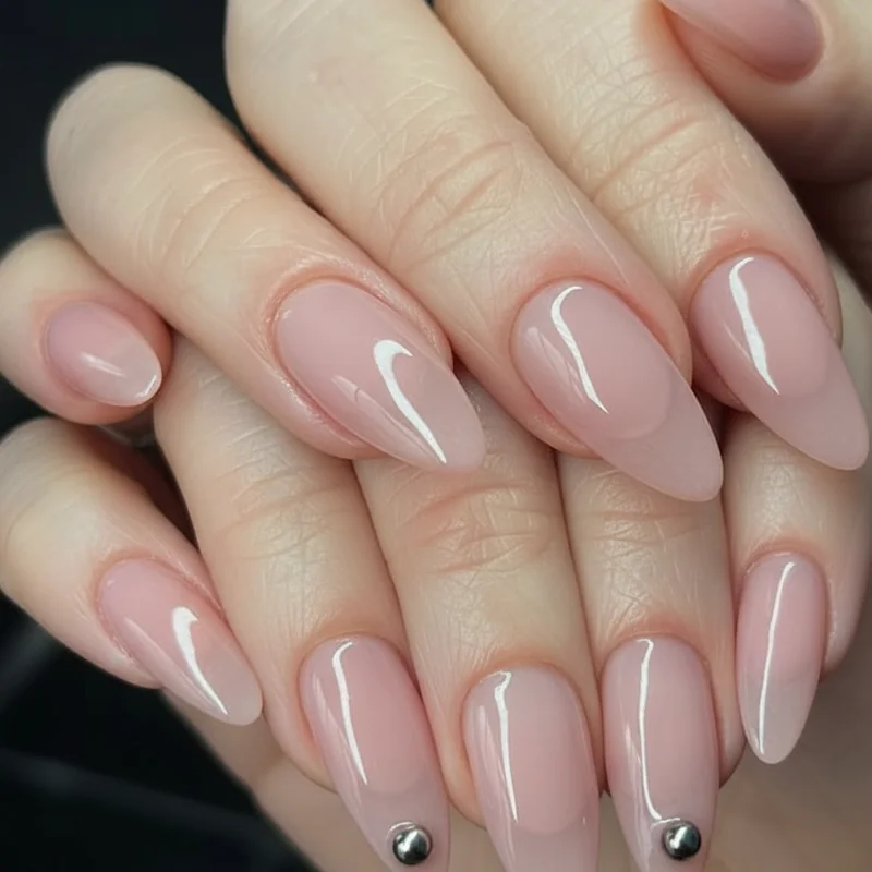 Pierced nail art with silver ball studs on sheer pearlescent pink base suggesting nipple piercing bar minimalist punk body modification look