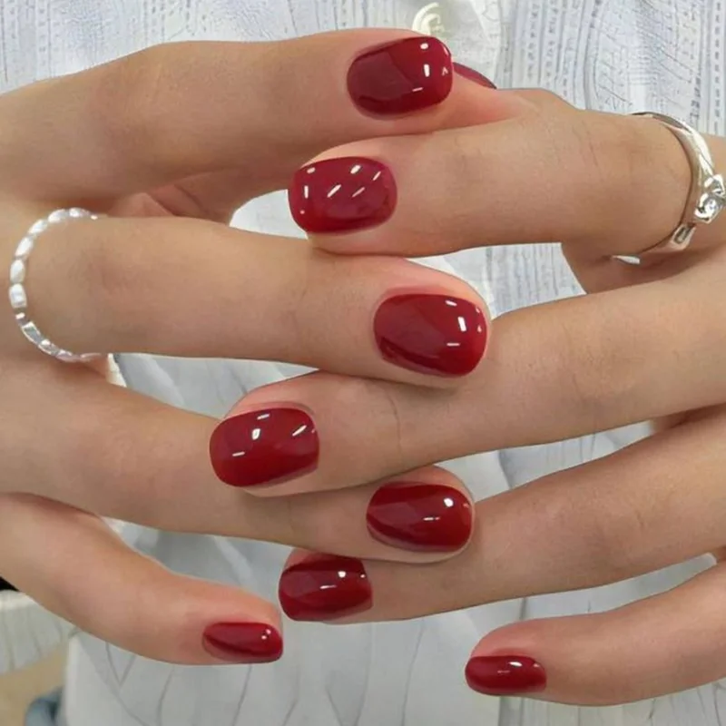 Classic warm red nail polish on mature hands with elegant oval shape showing timeless sophistication