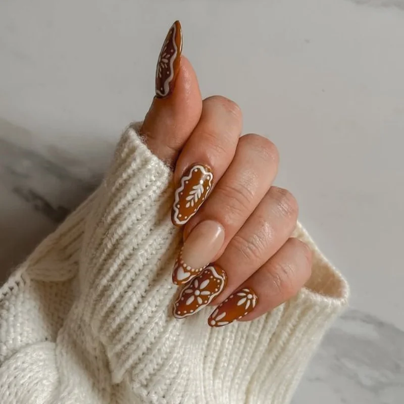 Decorated gingerbread man nail art with intricate white icing patterns and colorful candy details