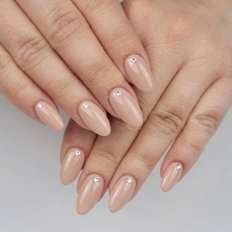 Diamond nails single cuticle gem accent on a glossy nude base manicure, showing a minimal everyday placement idea for beginners