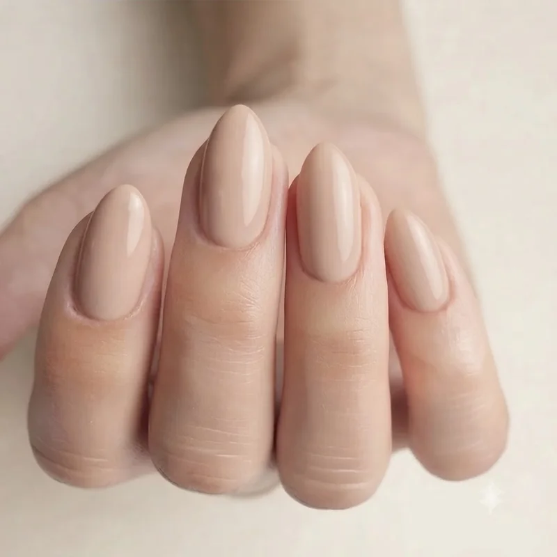 Short almond dip nails in a nude shade showing the tapered point that creates an elongating effect