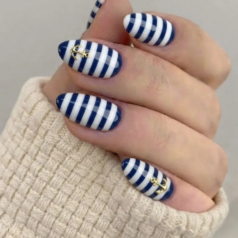 Navy and white nautical stripe nails with a gold anchor accent on almond shaped tips