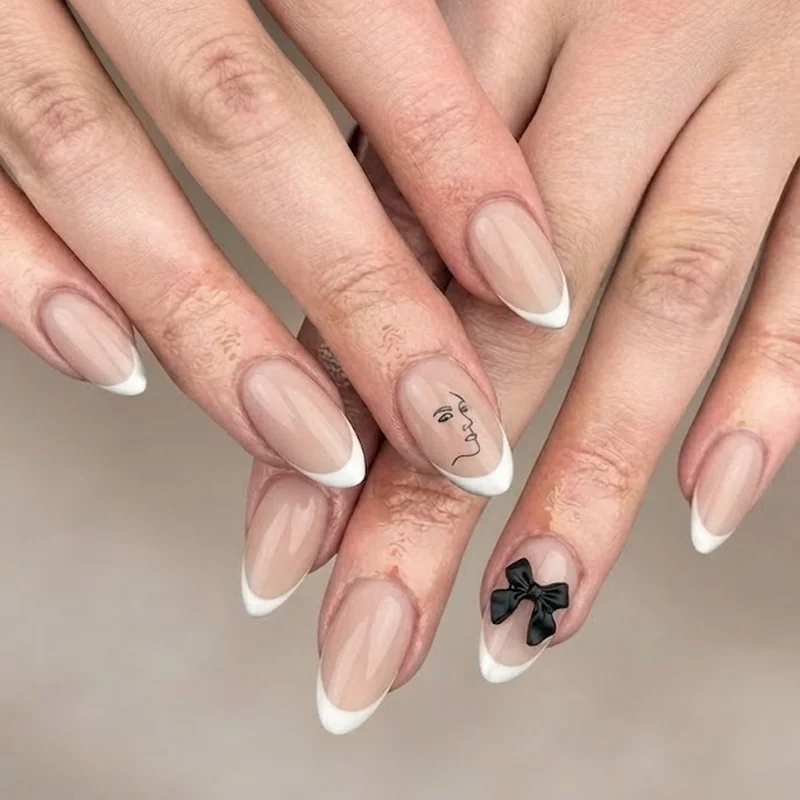 Nude French tip disney world nails with a tiny black Mickey silhouette and dainty bow accent detail