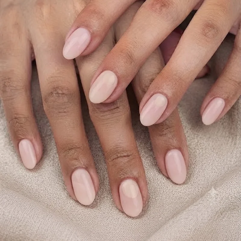 Short almond shaped nails in pastel pink with a subtle Mickey silhouette, park-ready length for Disney World