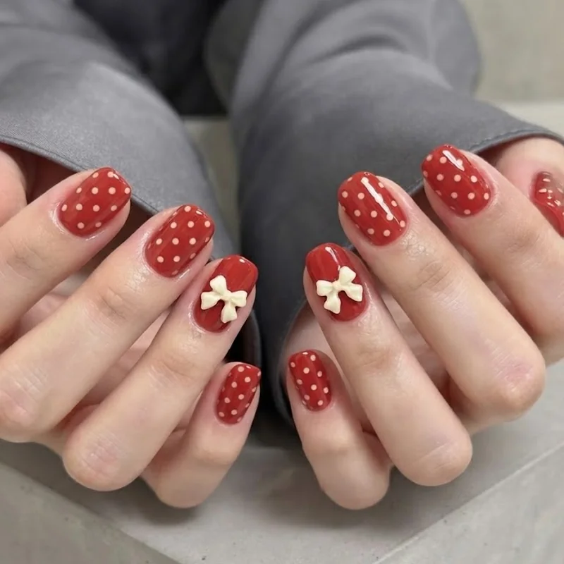 Short minnie mouse nails featuring red polka dot bow design on squoval shape