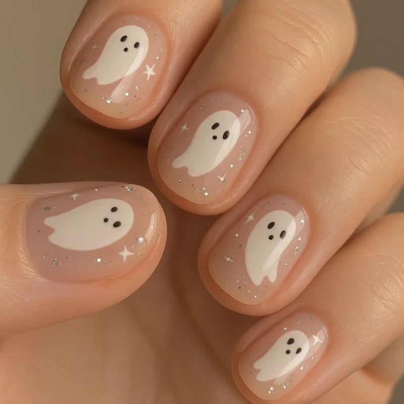 Simple white ghost nail art with black dot eyes on nude base coat perfect for Halloween beginners