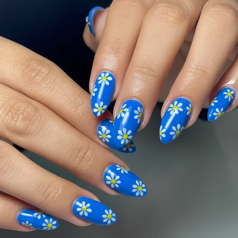 Daisy nail art in Insomniac EDC style featuring hand-painted white daisies with yellow centres on electric blue gel base for festival manicure