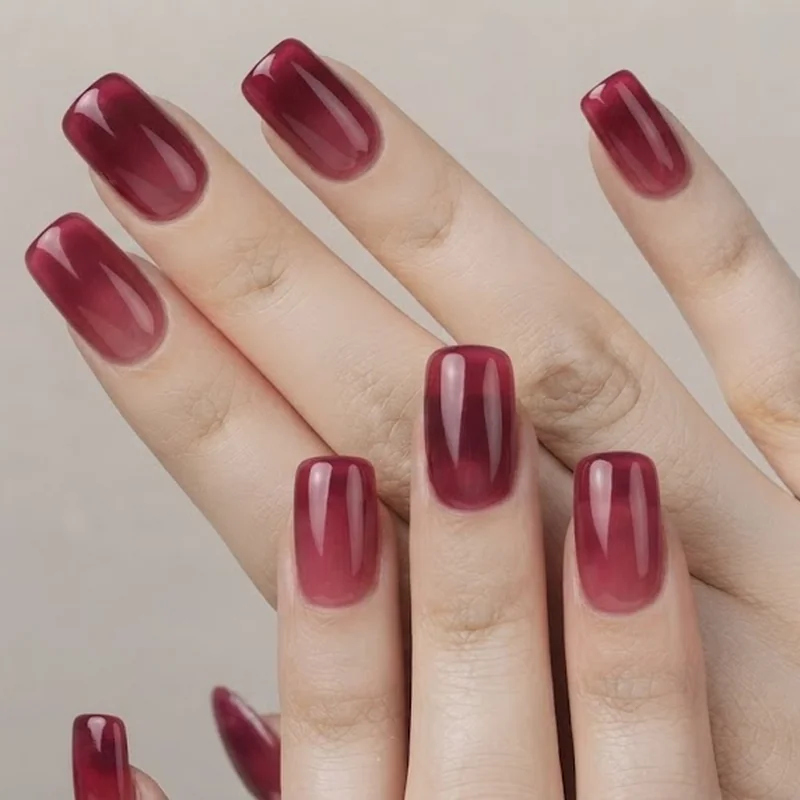 Close up of a cherry jelly finish manicure showing translucent depth on short square end of august nails
