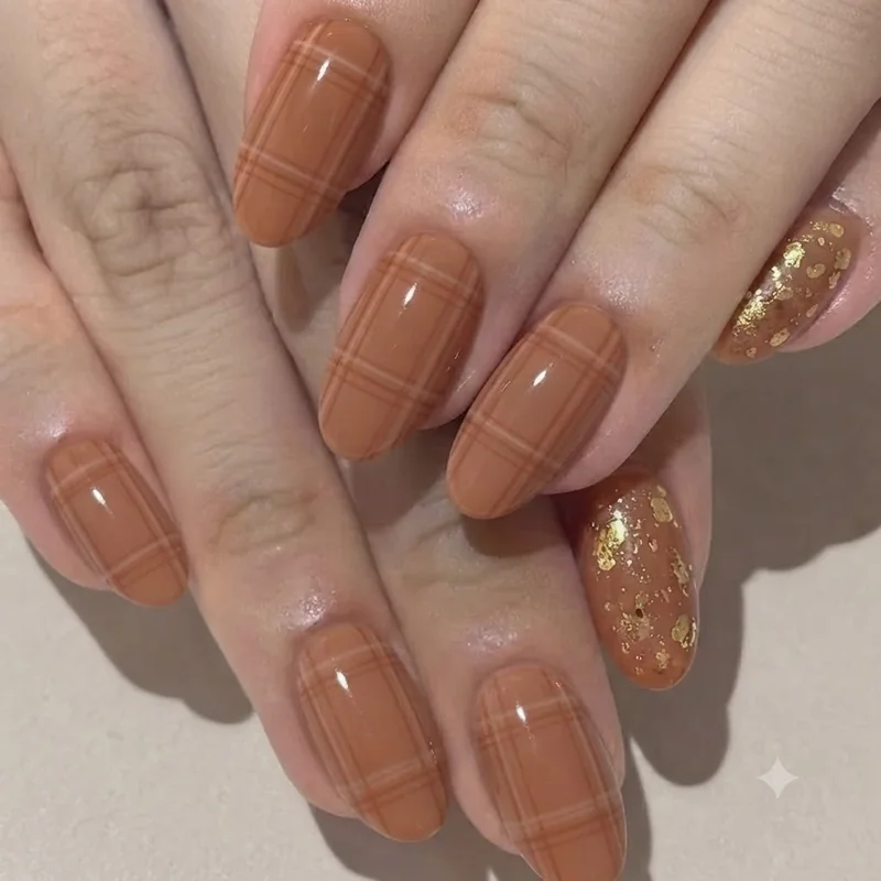 Augtober manicure blending cinnamon tones with subtle plaid detailing and a gold fleck accent nail