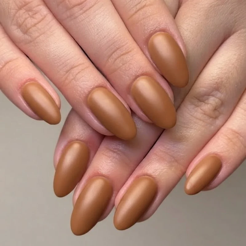 Editorial close-up of brown nails for fall styled with a knit sweater and coffee cup setting