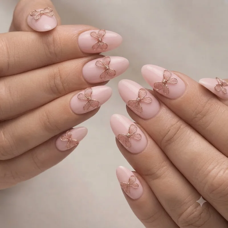 Almond-shaped coquette nail set on full hand with pink base and bow accent