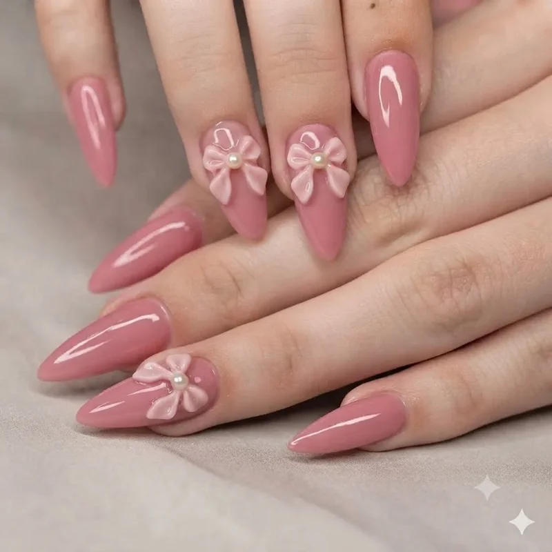 Classic pink coquette nails with a sculpted bow and pearl detail on ring finger