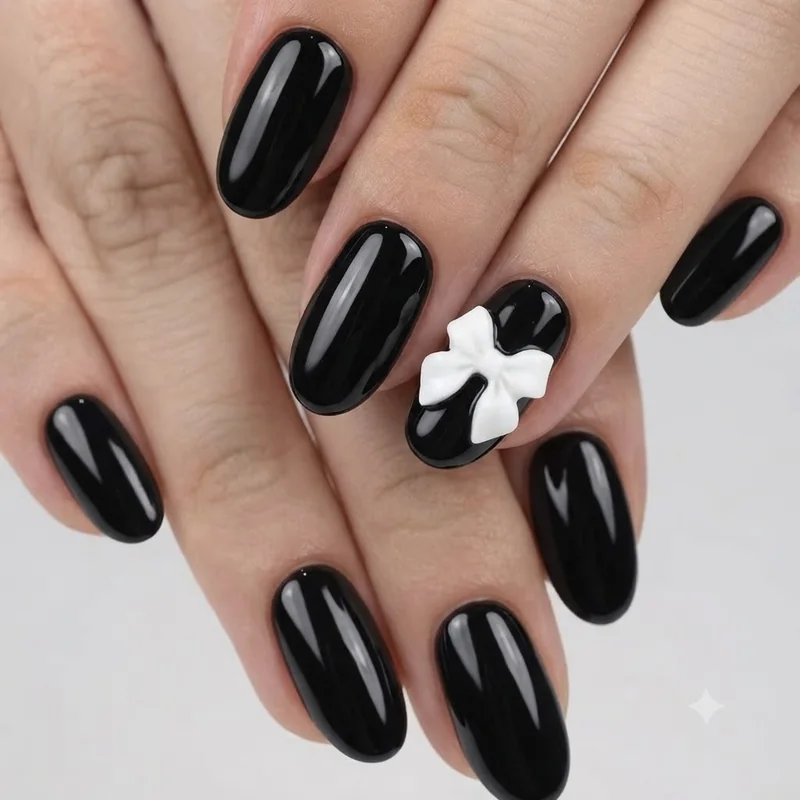 Glossy black dark coquette nails with white 3D sculpted bow accent nail detail