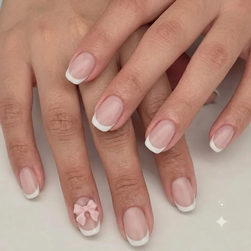 Classic white French tip Hello Kitty nails with small pink bow accent on ring finger