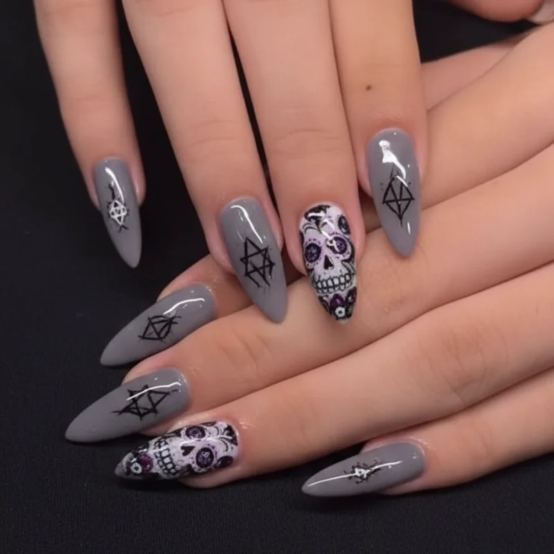 Dark pastel goth nails with muted lavender grey base featuring pentagram and sugar skull motifs for gothic edge aesthetic