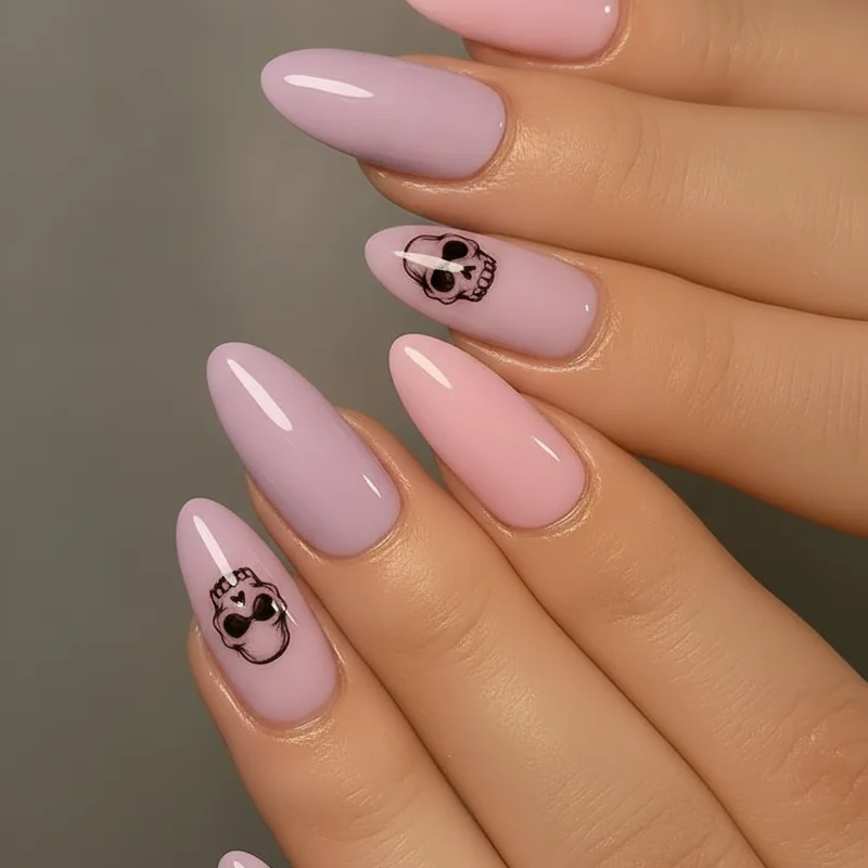 Pastel goth nail set featuring lavender and baby pink bases with black skull motifs in close-up flat lay aesthetic 2026