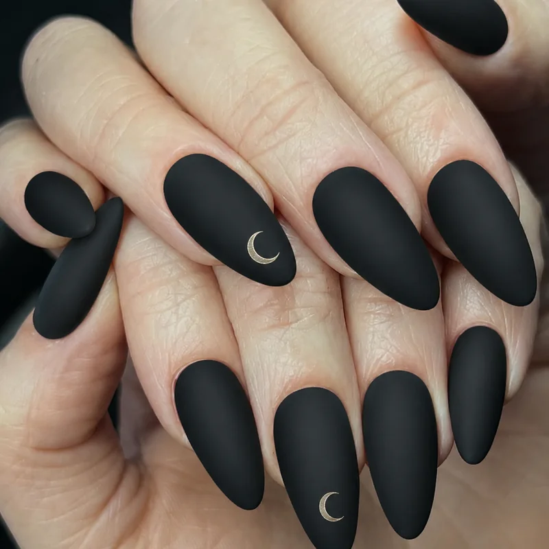Matte black witchy nails with crescent moon detail on almond shape showing minimalist occult aesthetic for everyday wearable witchy manicure