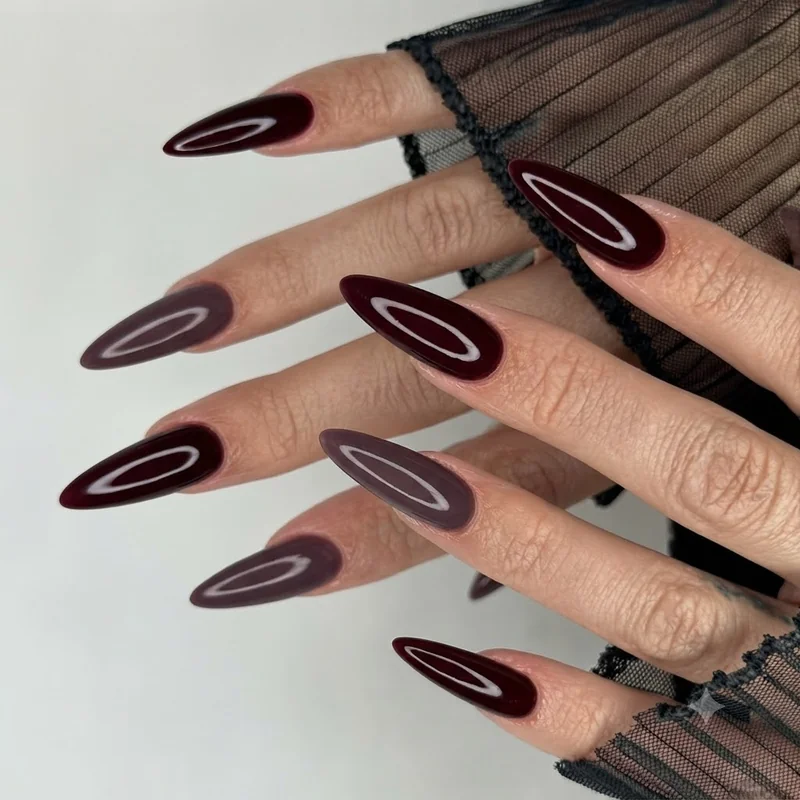 Glossy black cherry and oxblood gel manicure with one smoky plum accent nail, the dark red palette leading fall 2026 trends
