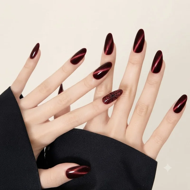 Oxblood velvet cat-eye almond manicure with a single micro spiderweb accent nail, a spooky-chic fall 2026 set to show a tech