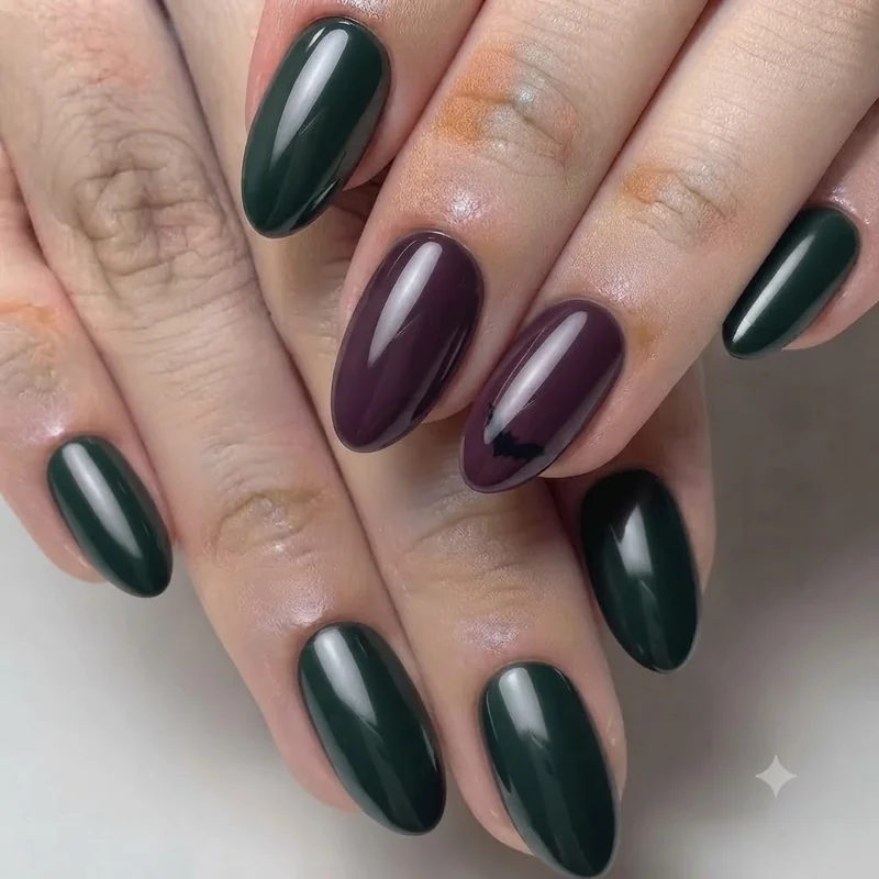 Short Halloween nails in plum and forest green with subtle black bat silhouette accent