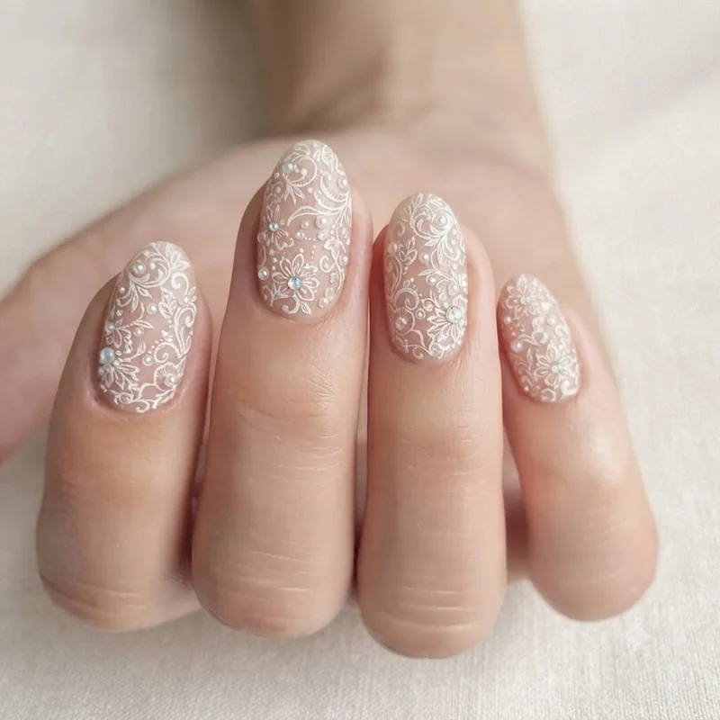 Bridal intricate nail designs with pearl lace detail and white filigree linework manicure