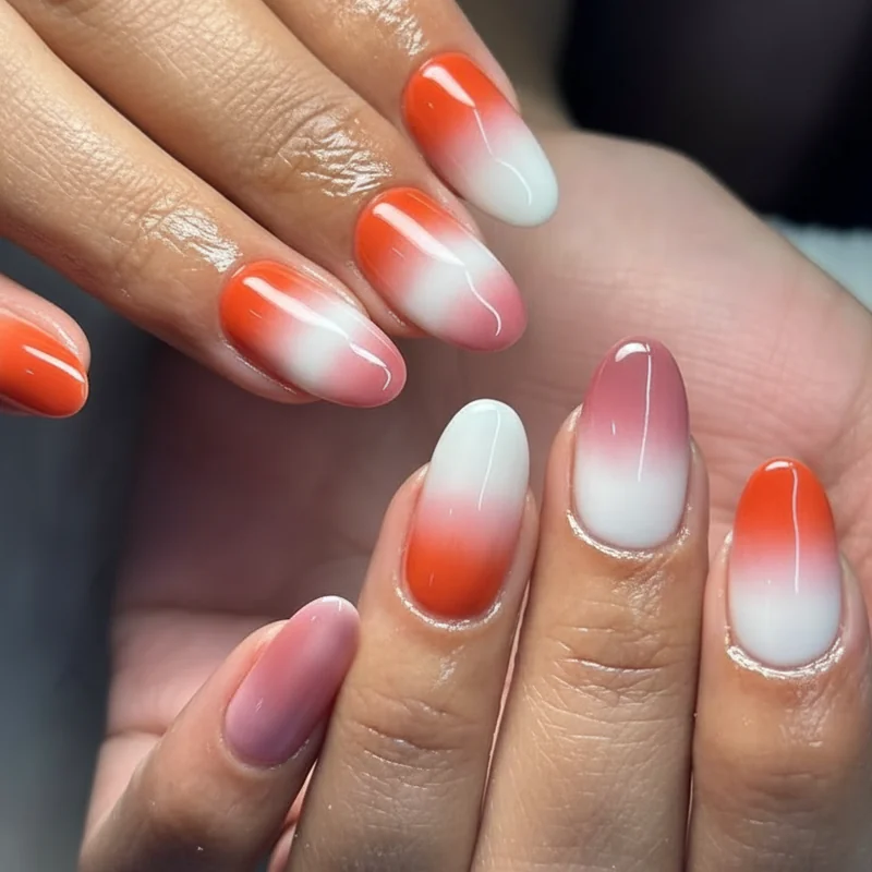 Sunset ombre lesbian flag nails showing makeup sponge gradient technique blending dark orange through white to deep pink on coffin nails