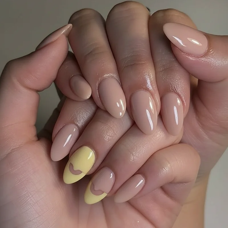 Enby accent nail designs showing ring finger in yellow flag colour against nude base with half moon and negative space variations for nonbinary pride