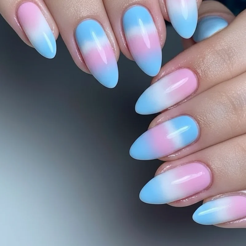 Trans flag ombre nails showing soft blue to pink to white gradient blend across almond shaped nails using sponge technique for seamless fade