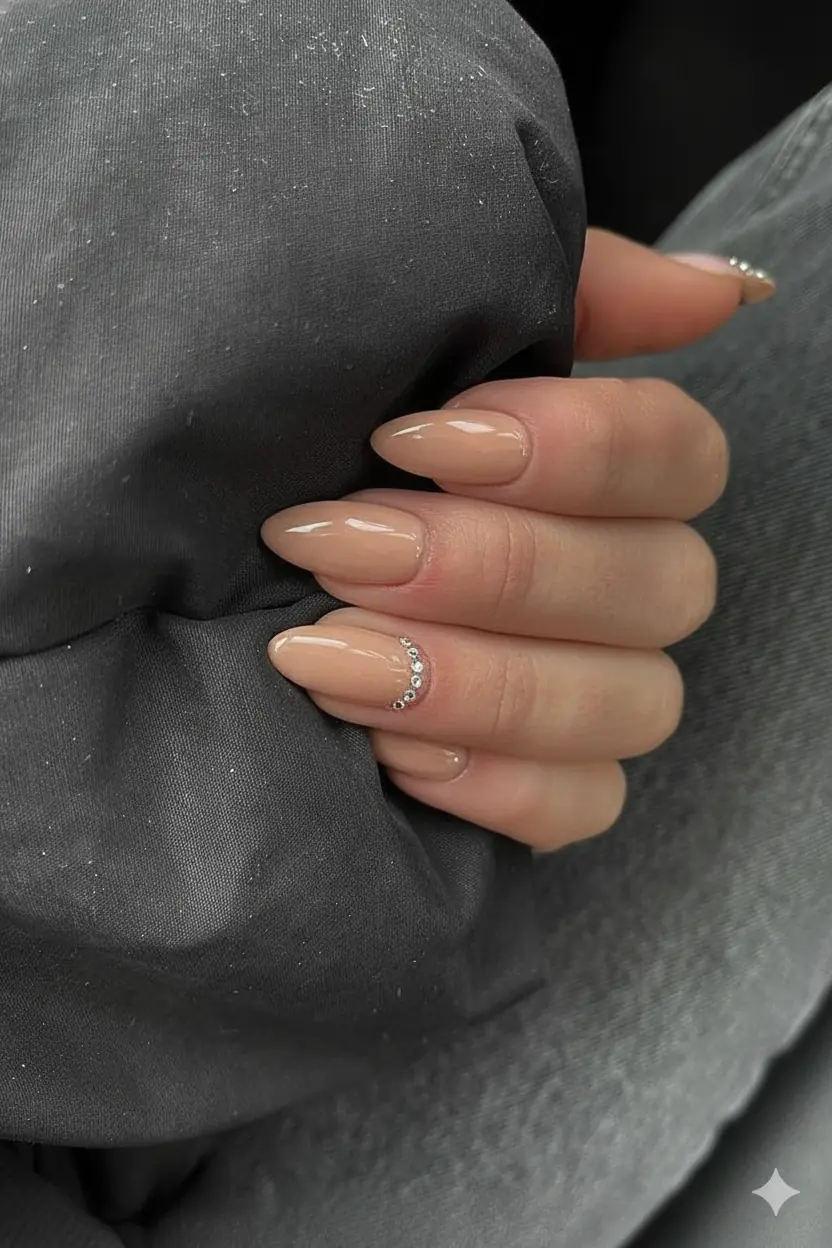 Warm neutral crystal cuticle detail mothers day nail 2026 elegant refined look single rhinestone at base of nail subtle luxury