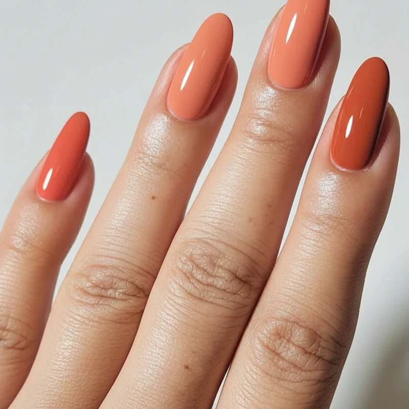Coral peach terracotta burnt orange nail swatches on fair redhead skin showing warm amplifying effect for copper hair