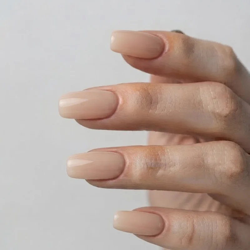 Round and squoval shaped gym nails in a natural nude gel manicure finish, shown on relaxed, clean-styled hands after a fill