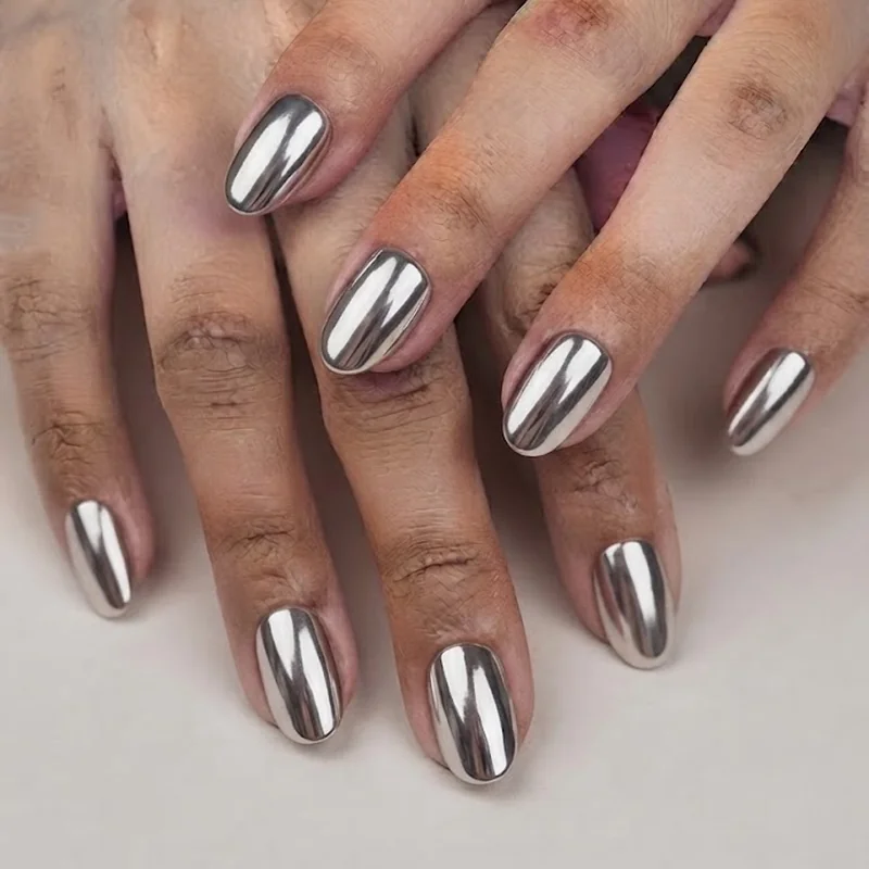 Chrome nails new years eve finished mirror manicure styled beside a full champagne glass at a midnight party toast scene