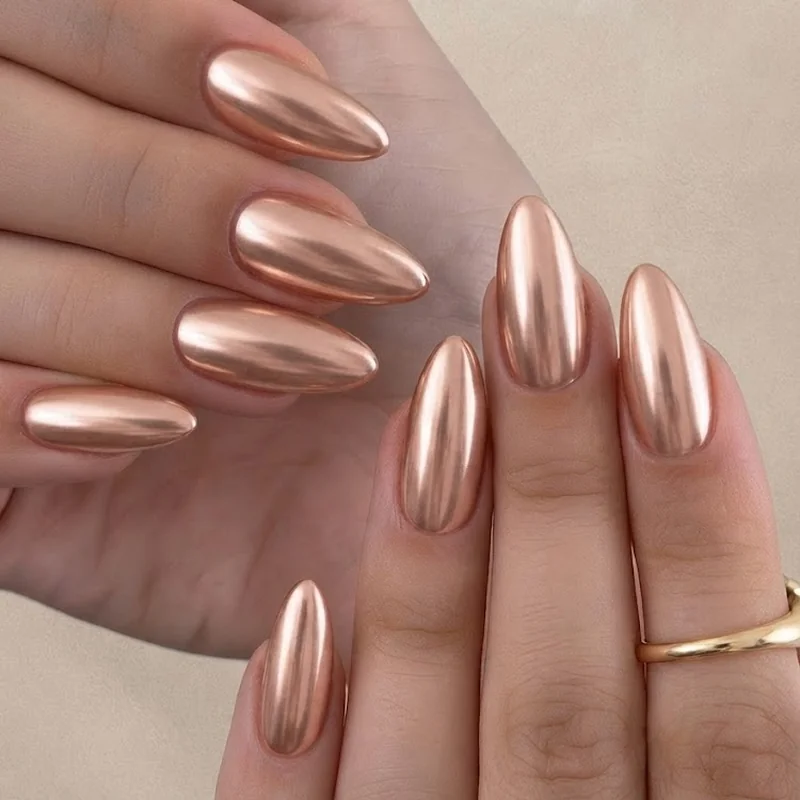 Rose gold chrome nails new years eve manicure over a sheer nude base, short almond shape, warm glam finish for the night
