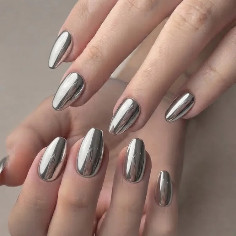 Full silver mirror chrome nails new years eve manicure on coffin shaped nails under festive party lighting for the night