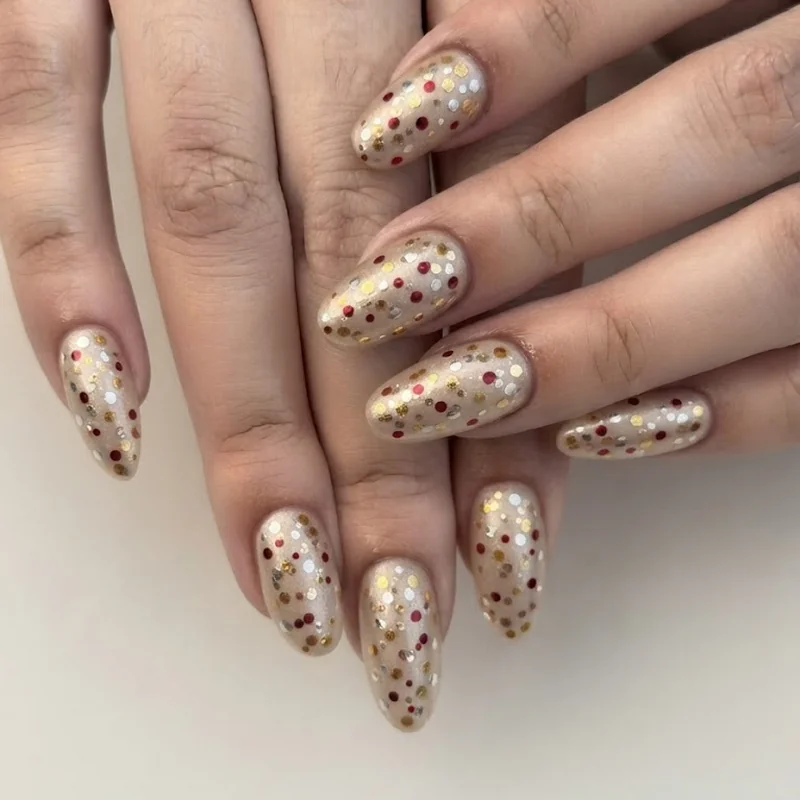 Confetti dot nails with gold red and silver polish scattered on a champagne base for NYE