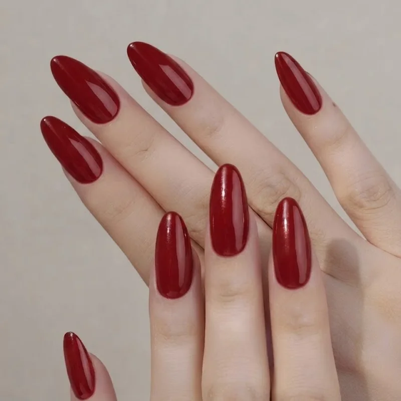 Wet look glossy red manicure in an almond shape with high shine top coat finish