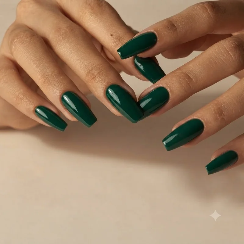 Deep emerald jewel tone nail polish for olive skin: glossy forest green manicure on an olive hand in warm window daylight