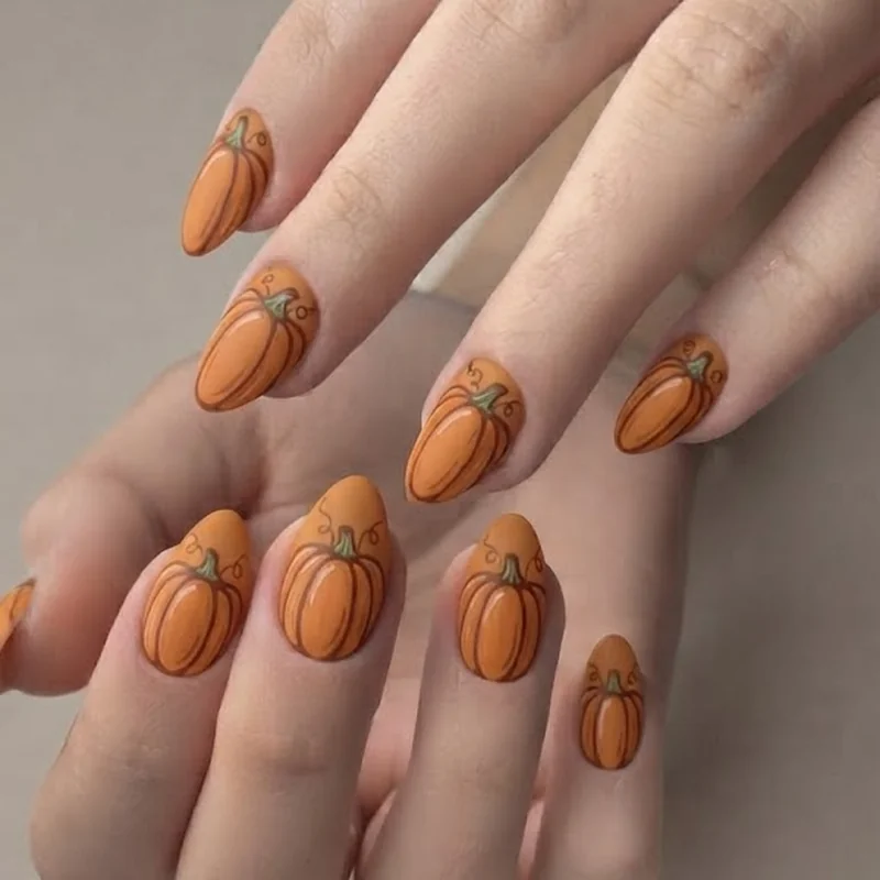 Classic rounded pumpkin nail art with orange base and brown outline detail on natural nails