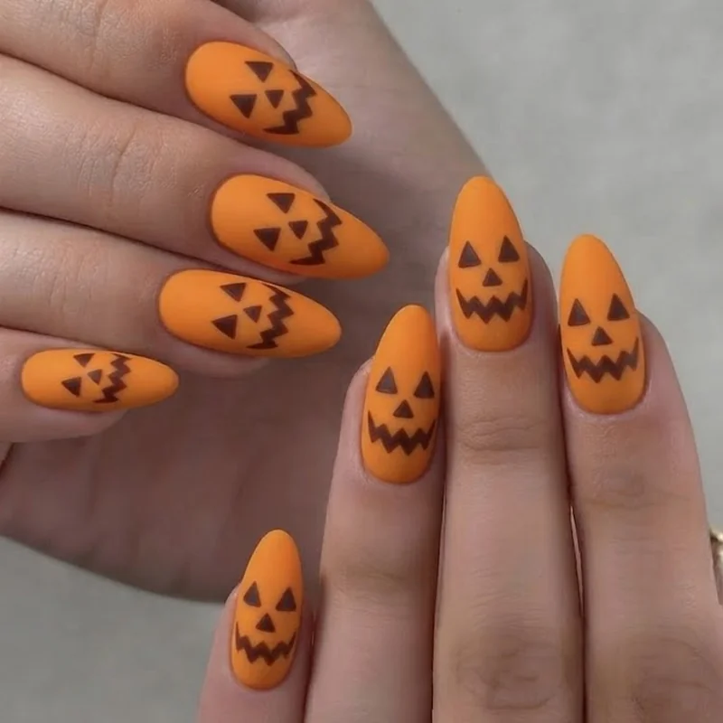 Jack-o-lantern face pumpkin nail art design showing carved triangle eyes and zigzag mouth detail