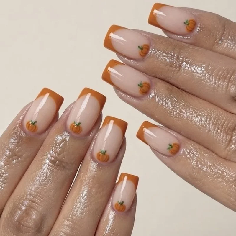 Pumpkin French tip manicure with curved orange tip design and stem detail over nude base