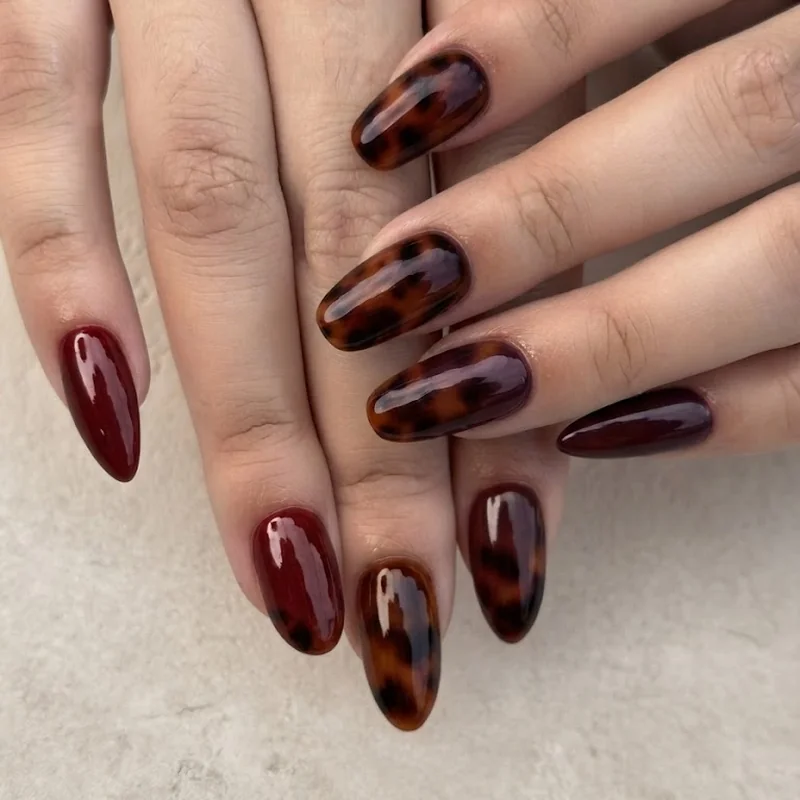 Short squoval october nails in tortoiseshell pattern with burgundy and amber tones